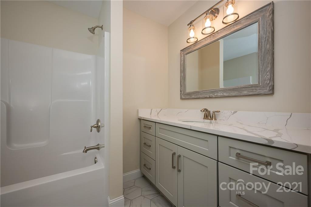 438 Gilbert Road Columbus, NC 28722 - Photo 18 of 46 a bathroom with a granite countertop sink vanity mirror bathtub and shower