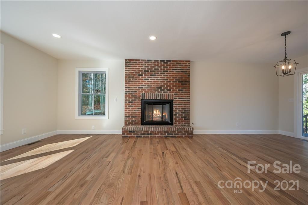 438 Gilbert Road Columbus, NC 28722 - Photo 6 of 46 an empty room with wooden floor fireplace and windows