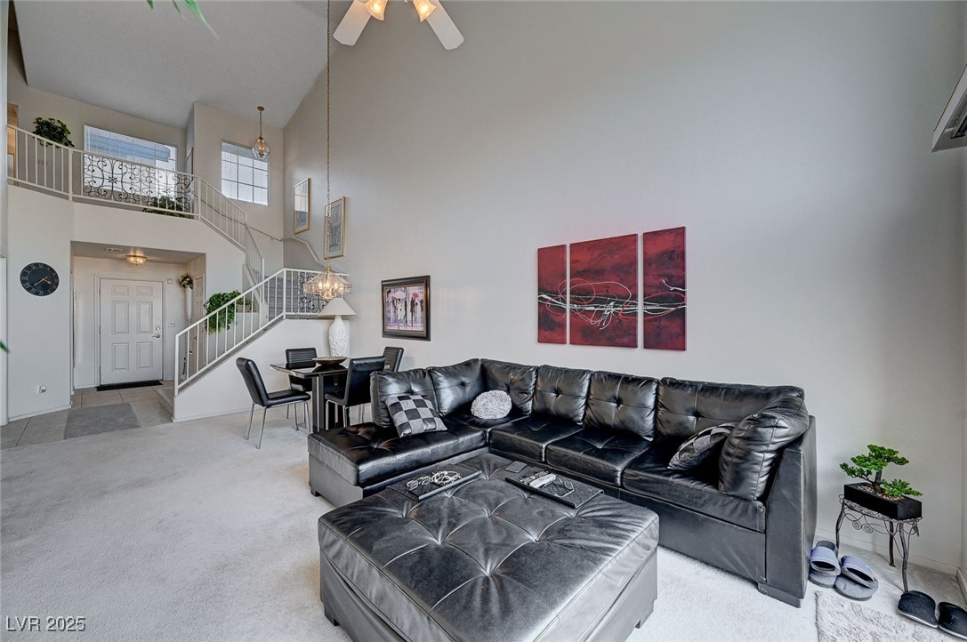 516 Crimson View Place Las Vegas, NV 89144 - Photo 11 of 66 Living room featuring light carpet, a towering ceiling, stairway, ceiling fan, and a chandelier