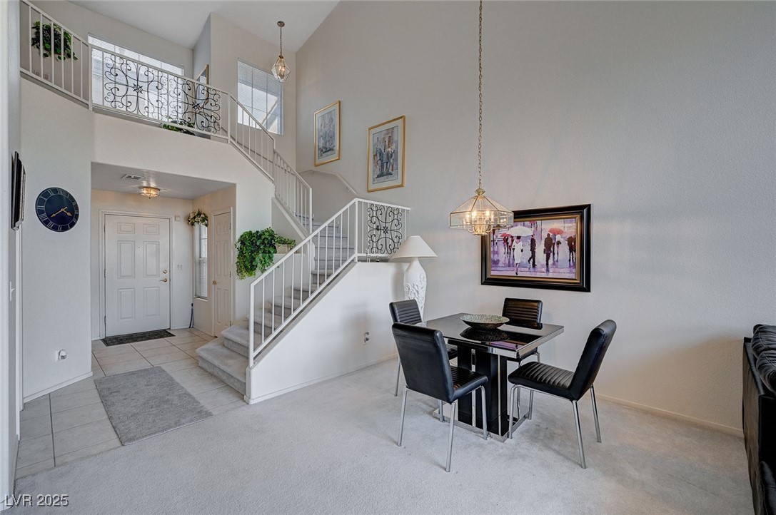 516 Crimson View Place Las Vegas, NV 89144 - Photo 12 of 66 Carpeted dining space featuring a chandelier, stairs, a towering ceiling, and tile patterned floors