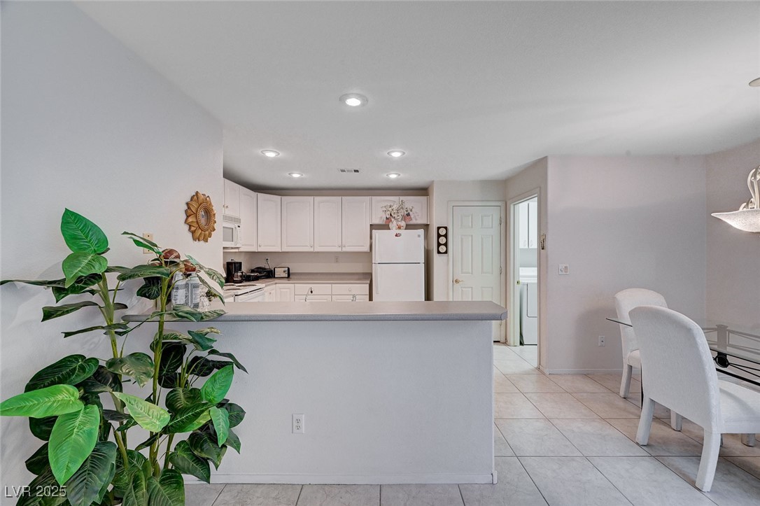 516 Crimson View Place Las Vegas, NV 89144 - Photo 16 of 66 Kitchen with white cabinetry, white appliances, light tile patterned flooring, light countertops, and a peninsula