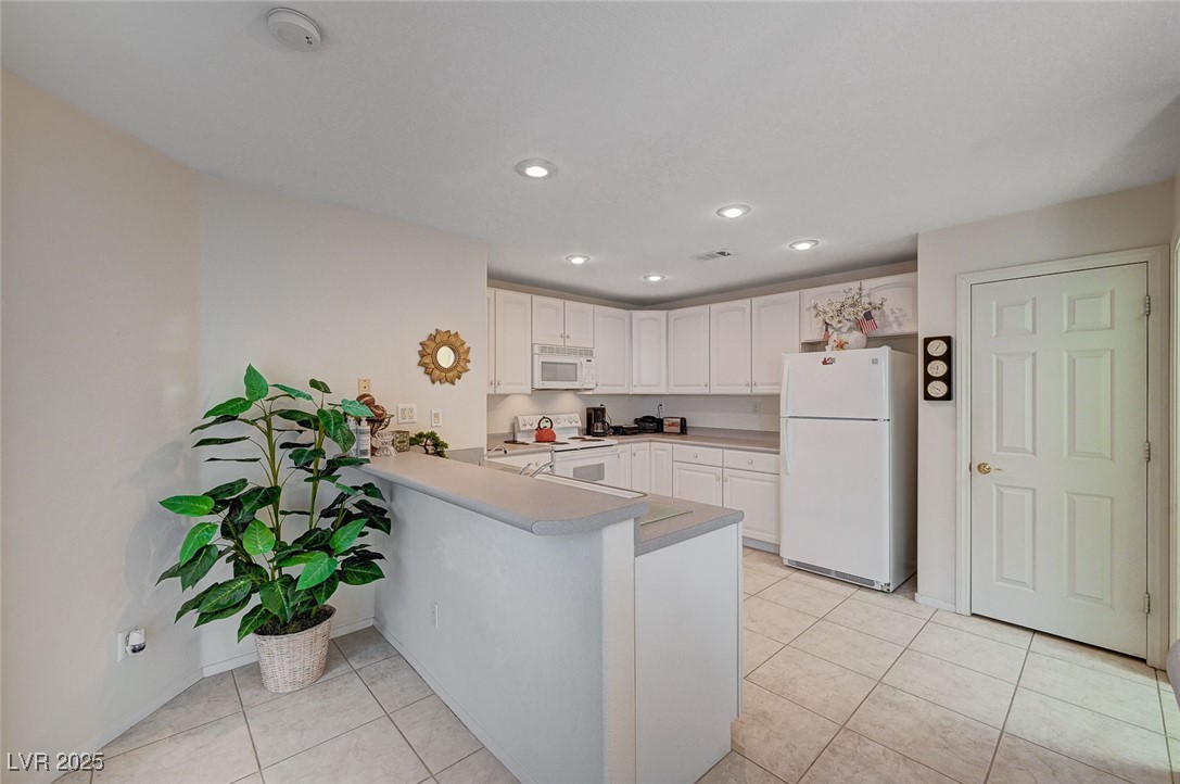 516 Crimson View Place Las Vegas, NV 89144 - Photo 20 of 66 Kitchen with white appliances, white cabinetry, light tile patterned flooring, recessed lighting, and a peninsula