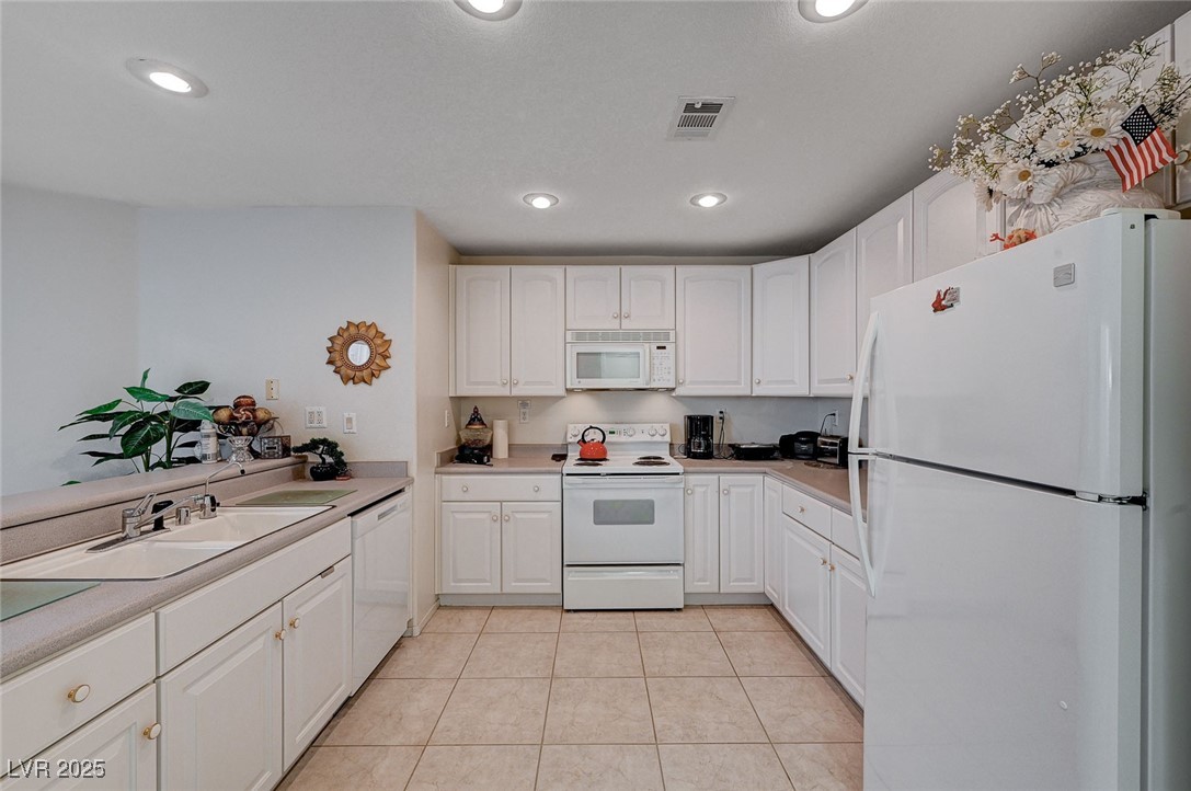 516 Crimson View Place Las Vegas, NV 89144 - Photo 21 of 66 Kitchen with white appliances, white cabinets, light tile patterned flooring, recessed lighting, and light countertops