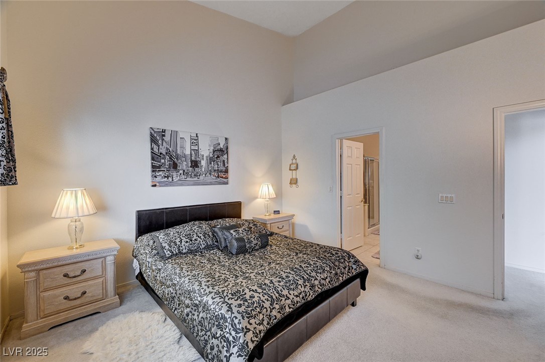 516 Crimson View Place Las Vegas, NV 89144 - Photo 29 of 66 Bedroom featuring light colored carpet, a towering ceiling, and ensuite bathroom