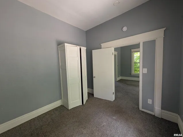 an empty room with closet and mirror