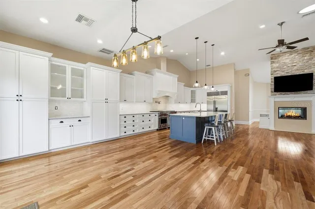 a kitchen with granite countertop a stove a sink a dining table and chairs with wooden floor