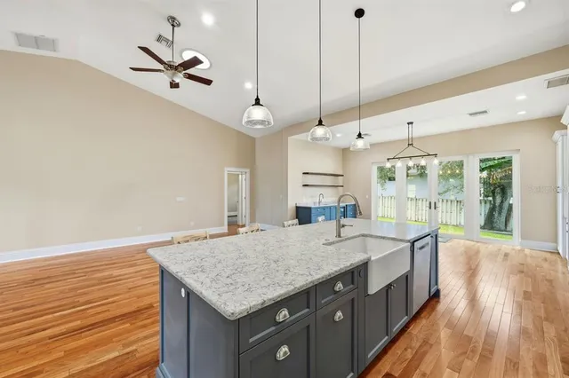 a large kitchen with stainless steel appliances kitchen island granite countertop a stove a refrigerator a sink dishwasher a dining table and chairs with wooden floor