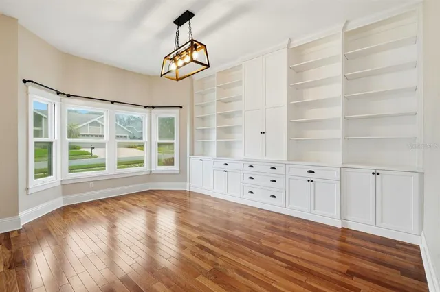 an empty room with wooden floor ceiling fan and windows