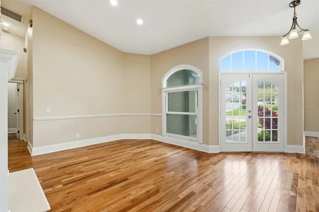 a view of empty room with wooden floor and fan