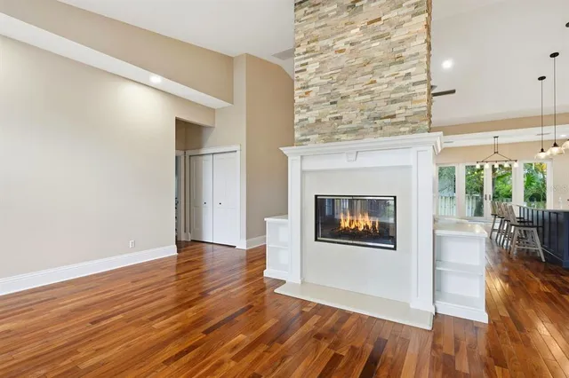 an empty room with wooden floor fireplace and windows