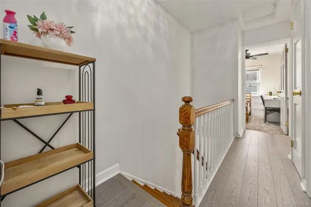 a view of a hallway to a livingroom with wooden floor and stairs