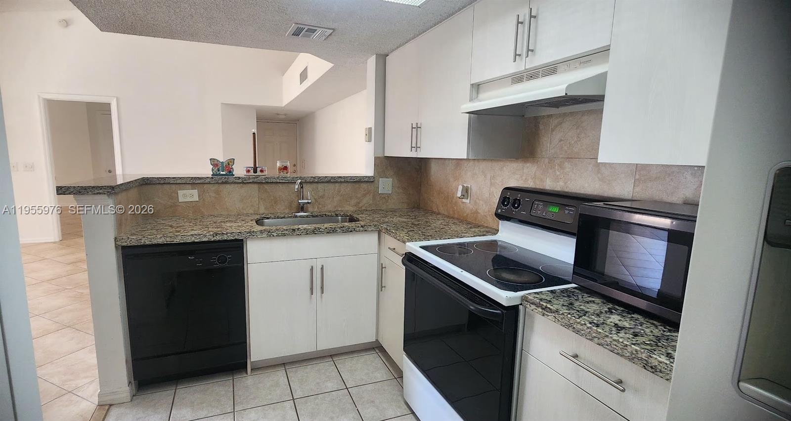 5011 Wiles Road, Unit 306 Coconut Creek, FL 33073 - Photo 6 of 17 a kitchen with granite countertop a stove sink and cabinets