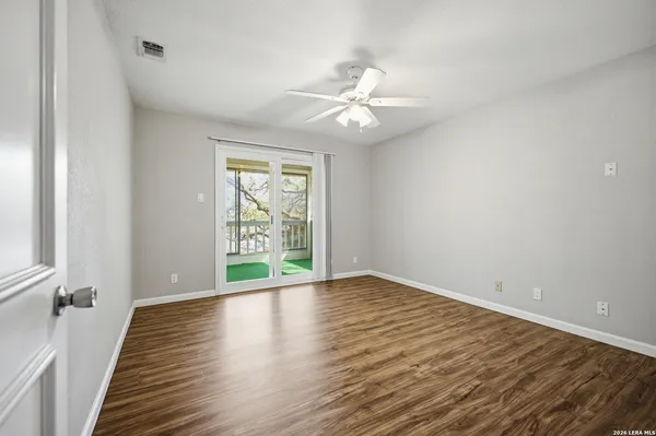 an empty room with wooden floor fan and windows