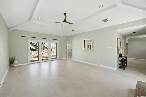 an empty room with ceiling fan and windows