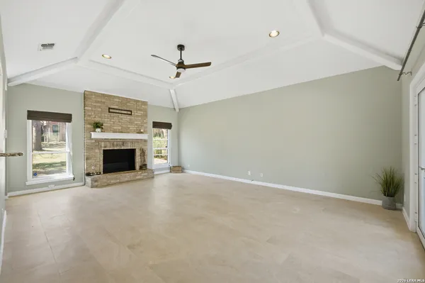 an empty room with fireplace and a ceiling fan