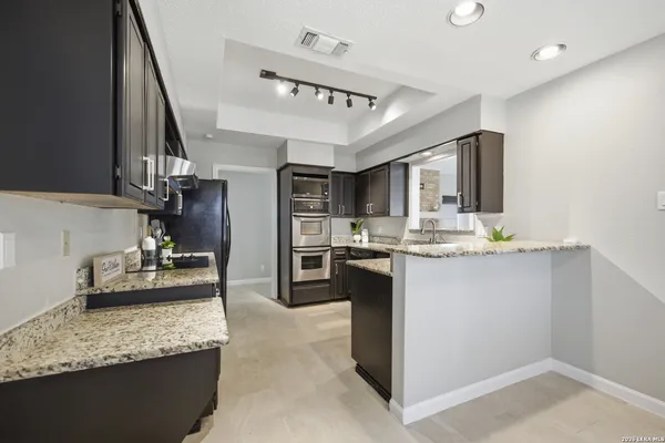 a kitchen with kitchen island granite countertop a sink stove and refrigerator