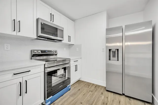 a kitchen with kitchen island white cabinets appliances and a chandelier