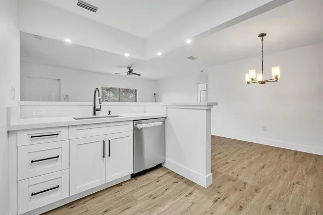 a kitchen with cabinets stainless steel appliances and wooden floor