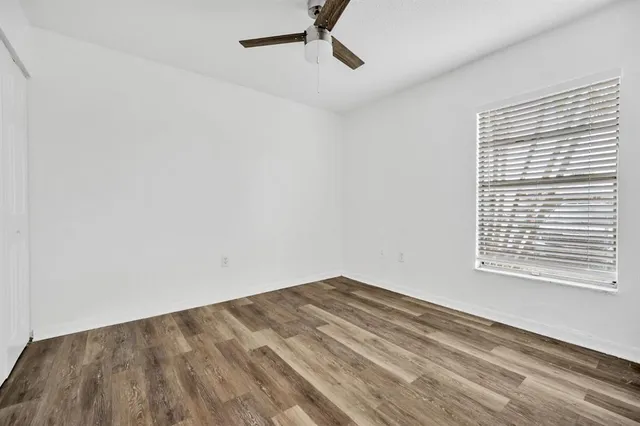 a view of empty room with wooden floor and fan
