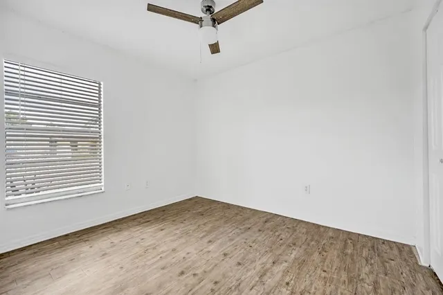 a view of empty room with wooden floor and fan