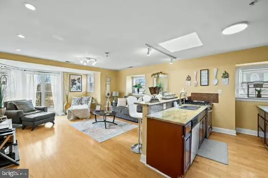 a large living room with stainless steel appliances granite countertop a couch and a large window