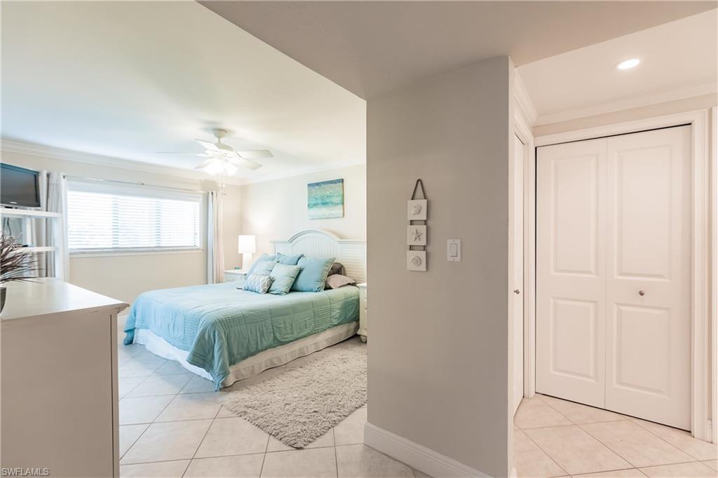 910 Vanderbilt Beach Road, Unit 311W Naples, FL 34108 - Photo 17 of 31 a bedroom with a large bed and a chandelier