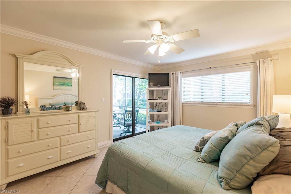 910 Vanderbilt Beach Road, Unit 311W Naples, FL 34108 - Photo 18 of 31 a bedroom with a large bed and a chandelier