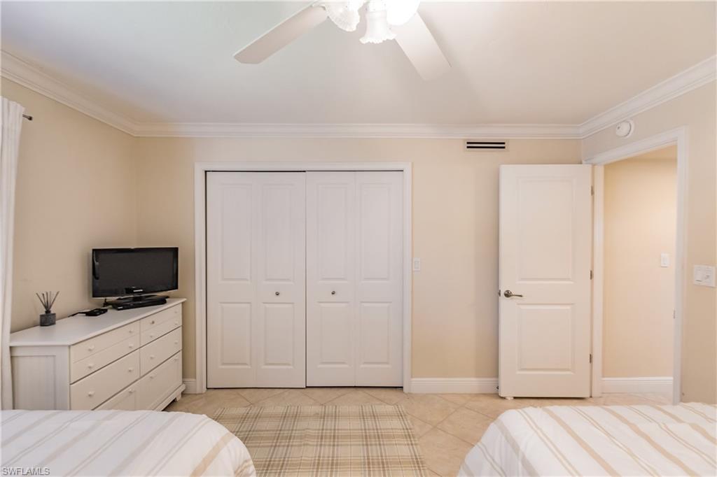 910 Vanderbilt Beach Road, Unit 311W Naples, FL 34108 - Photo 27 of 31 a bedroom with a bed and a flat screen tv