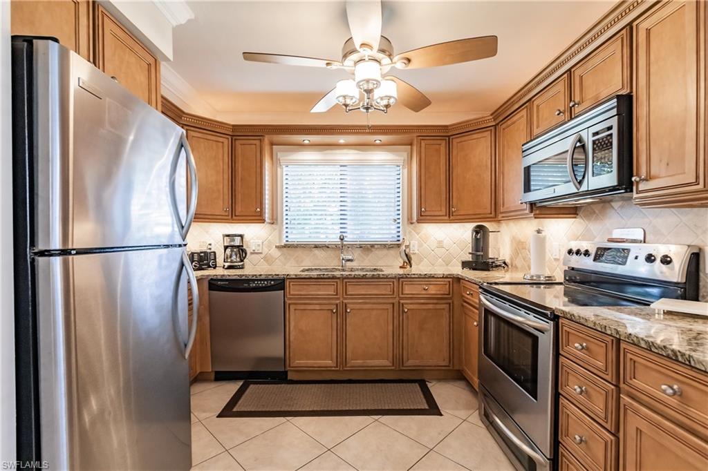 910 Vanderbilt Beach Road, Unit 311W Naples, FL 34108 - Photo 5 of 31 a kitchen with stainless steel appliances granite countertop a refrigerator sink stove microwave and cabinets