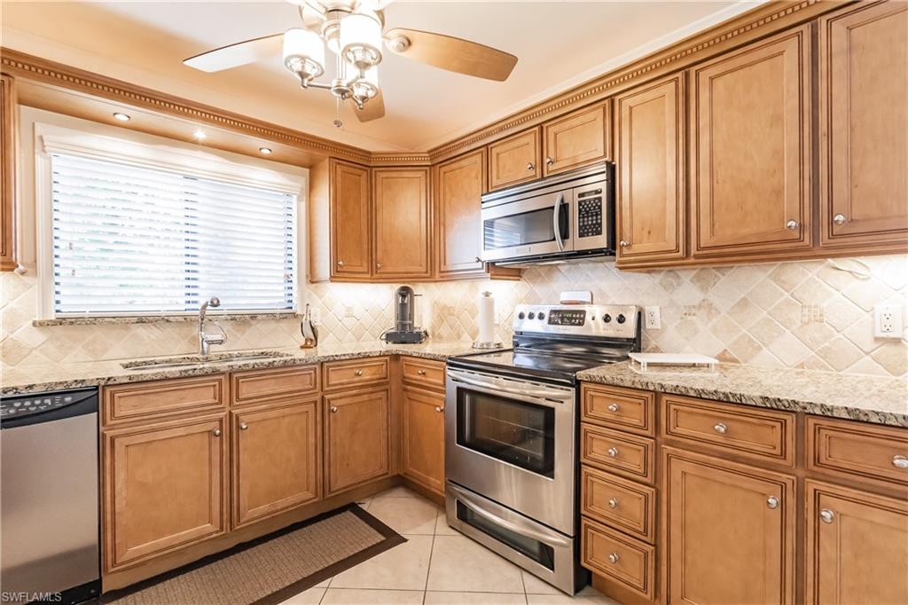 910 Vanderbilt Beach Road, Unit 311W Naples, FL 34108 - Photo 6 of 31 a kitchen with stainless steel appliances granite countertop a sink stove and microwave