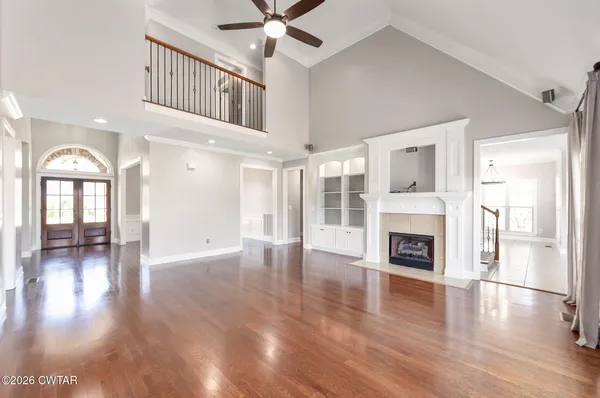 a view of an empty room with wooden floor fireplace and a window