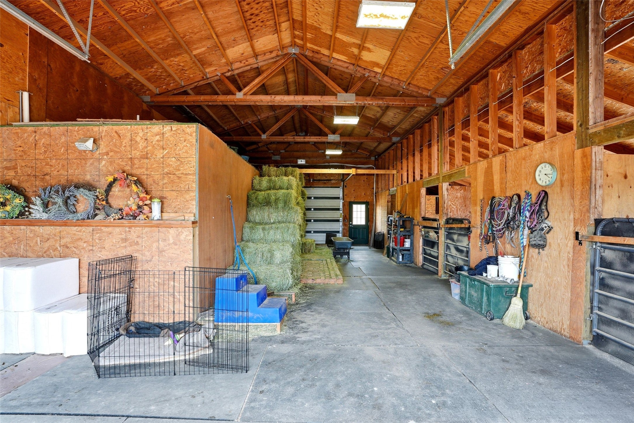 679 Hidden Valley Road North Florence, MT 59833 - Photo 54 of 85 Spacious barn interior featuring exposed wood beams, plywood wall construction, concrete flooring, and a large roll-up door