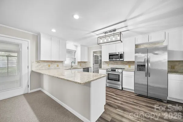 a kitchen with stainless steel appliances granite countertop a refrigerator and a stove top oven
