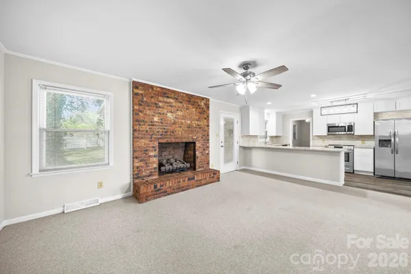 a view of a livingroom with a fireplace a ceiling fan and windows