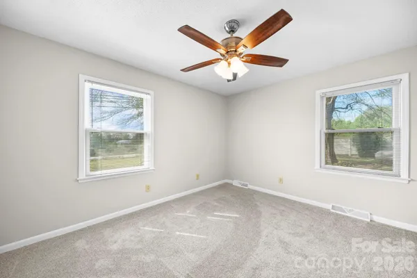 an empty room with a window and a fan