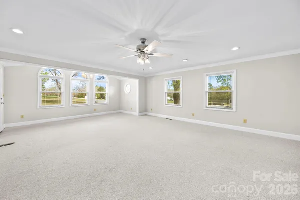 an empty room with windows and chandelier fan