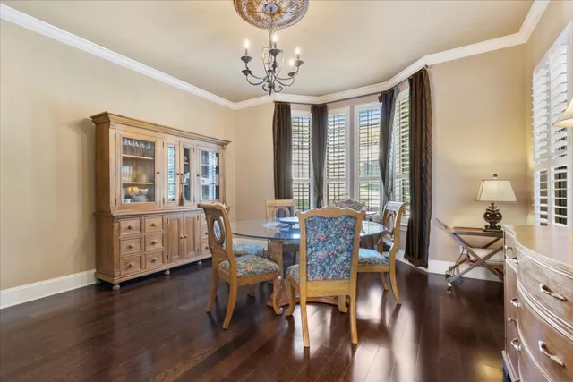 a dining room with wooden floor a chandelier a wooden table and chairs
