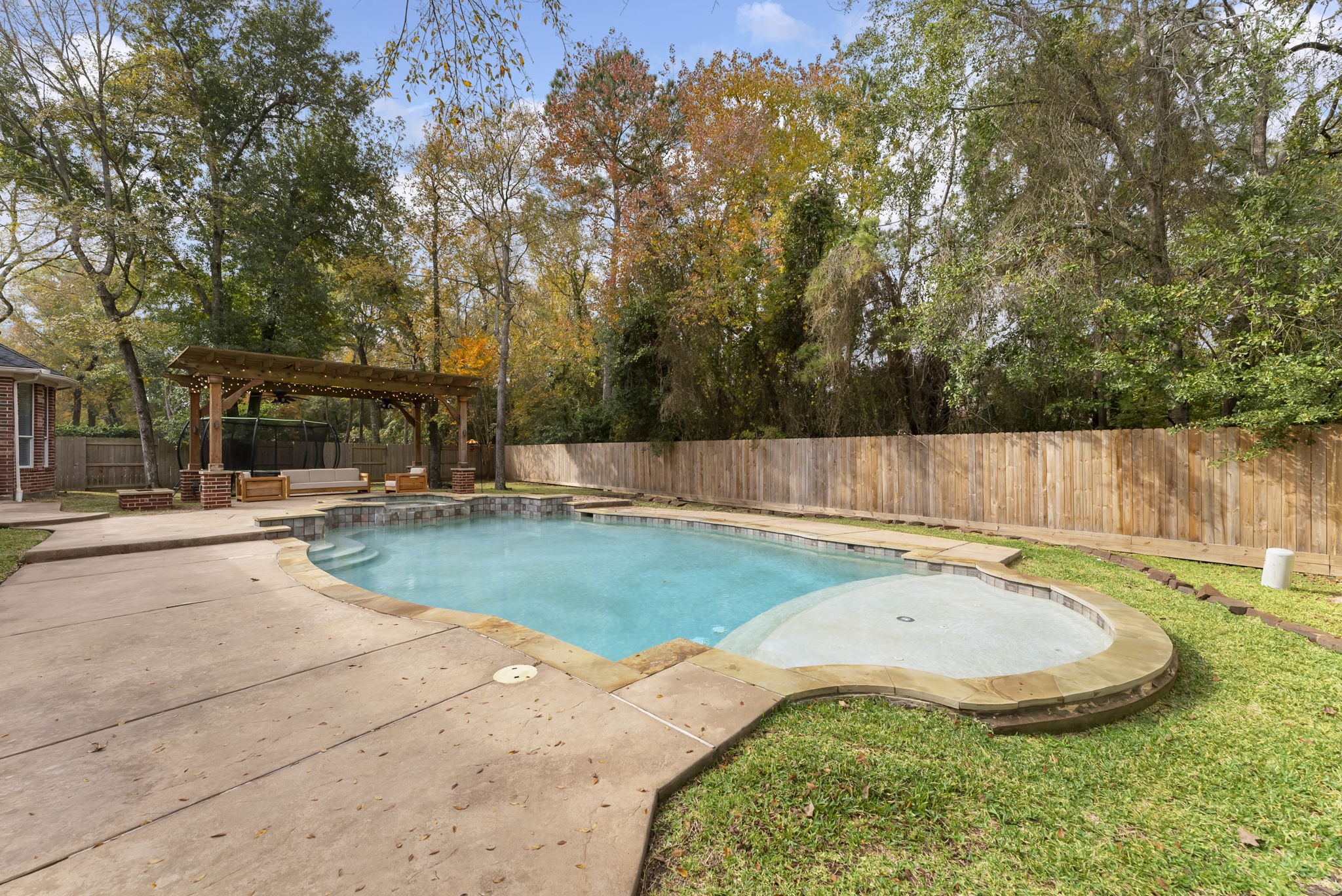 6 Lagato Place Spring, TX 77382 - Photo 34 of 42 A freeform pool with tanning ledge and surrounding patio creates a true backyard retreat. Designed for both relaxation and fun, with plenty of room for loungers and gatherings.