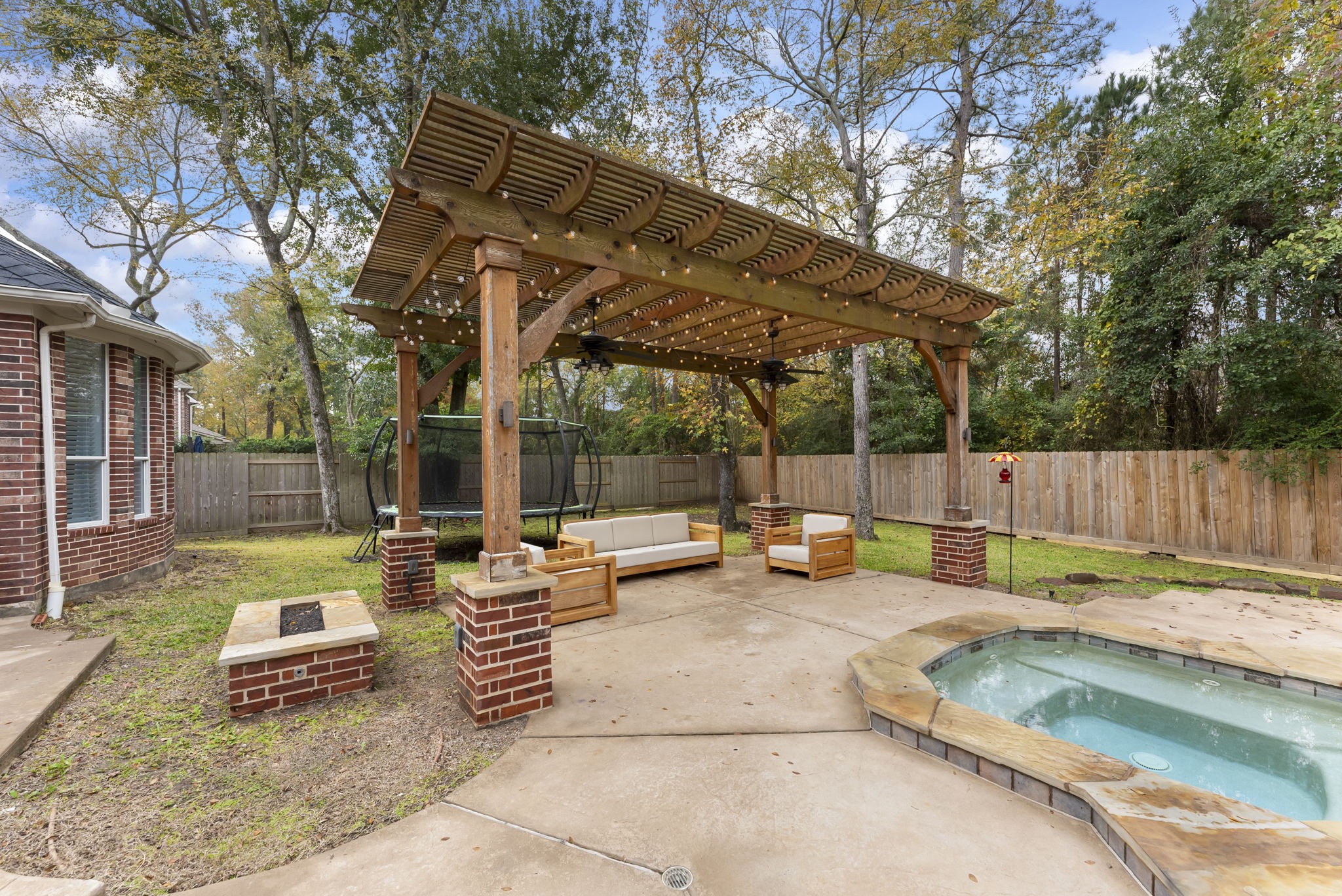 6 Lagato Place Spring, TX 77382 - Photo 37 of 42 A custom pergola with string lighting and ceiling fans anchors the outdoor living space beside the spa. Perfect for shaded lounging, evening entertaining, or quiet relaxation