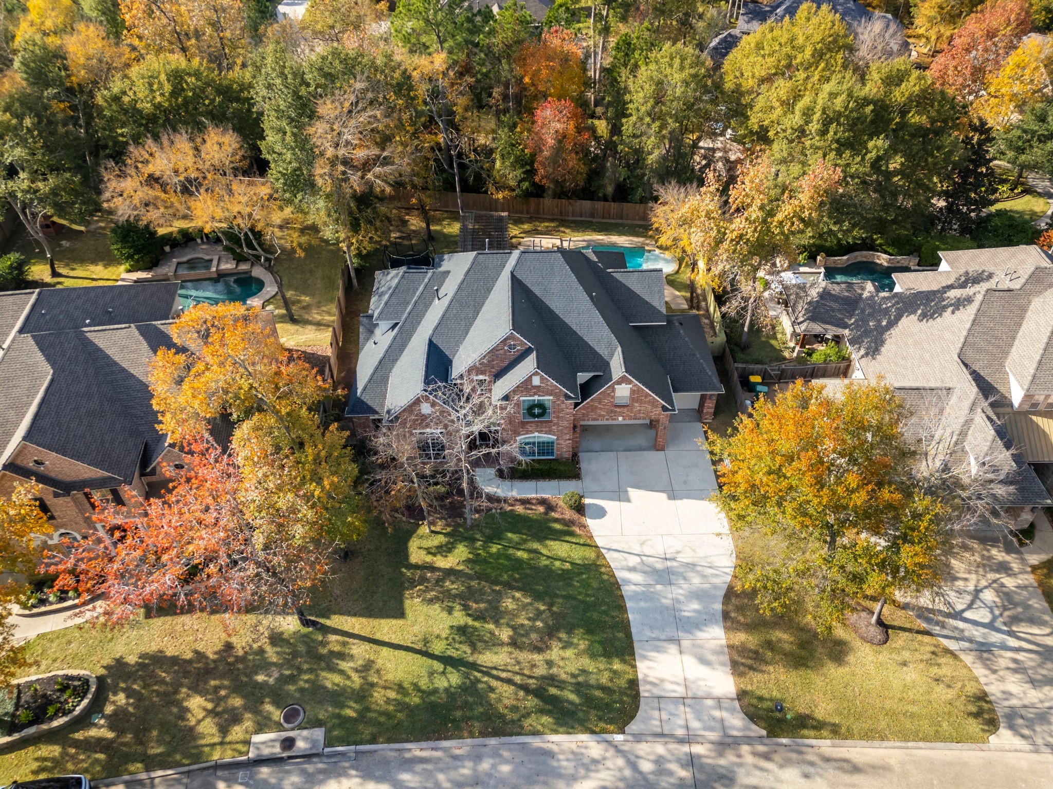 6 Lagato Place Spring, TX 77382 - Photo 40 of 42 An overhead perspective reveals a private backyard retreat with a pool, spa, pergola, and expansive lawn surrounded by natural greenery. With no neighbors directly behind, the outdoor space feels peaceful and secluded, ideal for entertaining, play, or quiet evenings at home.
