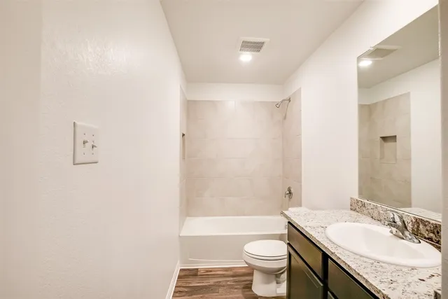 a bathroom with a granite countertop sink a toilet a mirror and bathtub