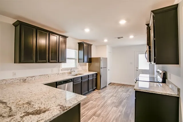 a kitchen with stainless steel appliances granite countertop a sink stove and refrigerator