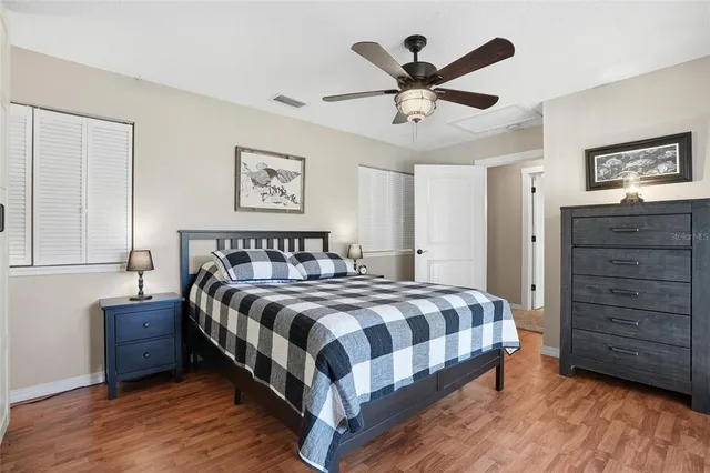 a bedroom with a bed a dresser and a ceiling fan