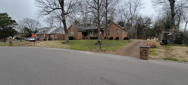 a front view of a house with a yard and trees