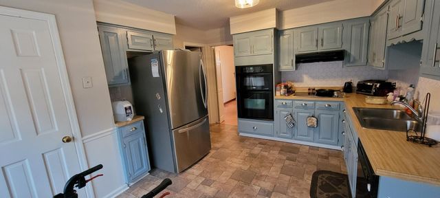 a kitchen with stainless steel appliances granite countertop a refrigerator a stove and a sink