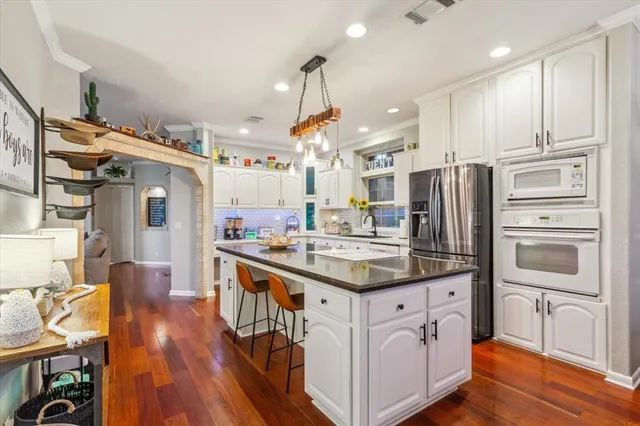 a kitchen with white cabinets and clock on the wall