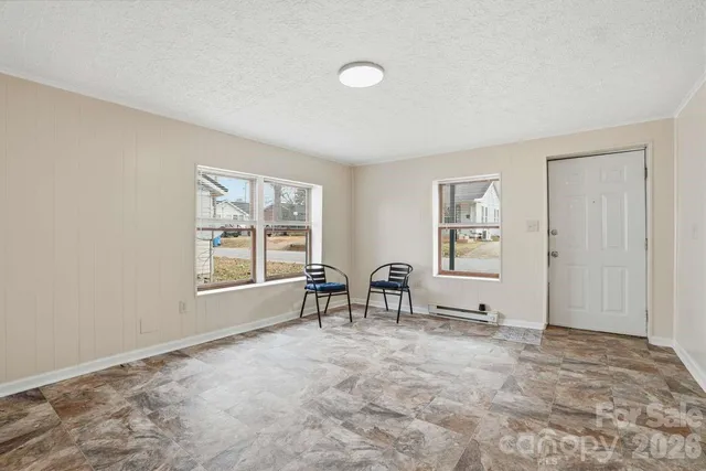 a view of an empty room with window and chair