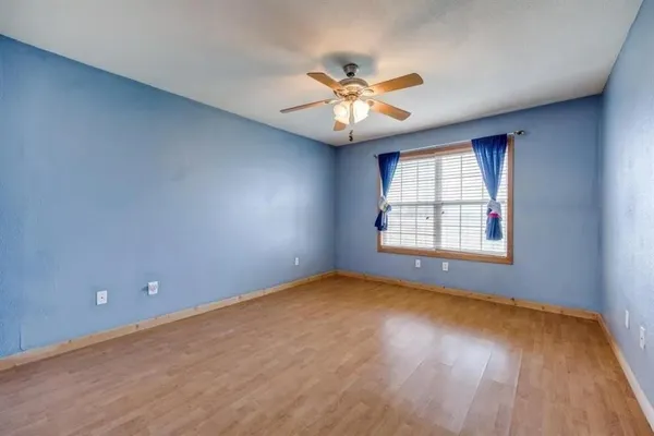 an empty room with windows and fan