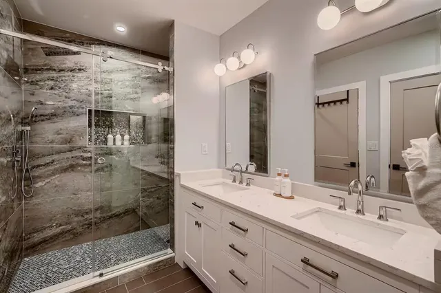 a bathroom with a double vanity sink mirror and shower