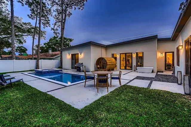 a view of a backyard with table and chairs potted plants and a large tree